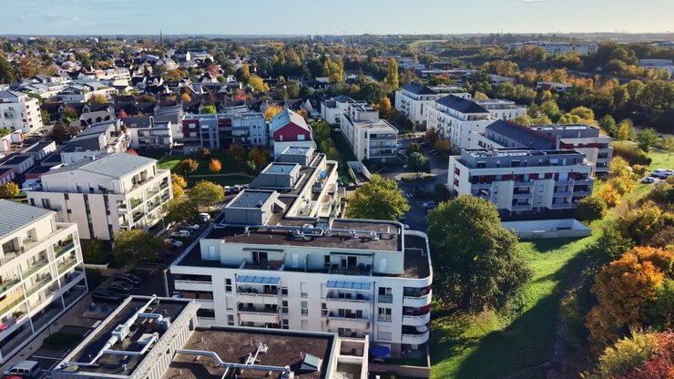 Wohnviertel mit moderner Architektur neben einem farbenfrohen Wald in Cesson-Sévigné, Frankreich. Drohnen-Luftaufnahme im Vorwärtsflug.