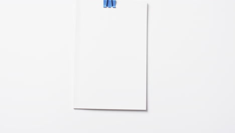 video of book with white blank pages and copy space hanging on clip on white background