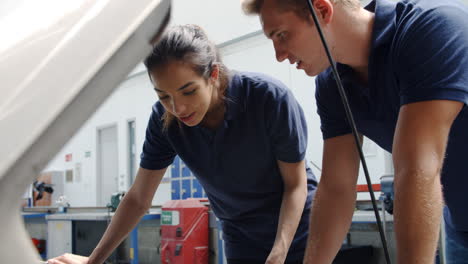 Two-Trainee-Mechanics-Studying-Car-Engine-At-College