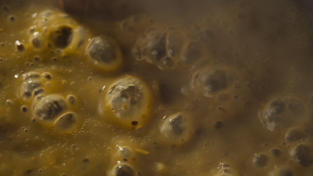 Green boiling sauce texture close-up macro. Cooking green curry with wooden spoon at home.