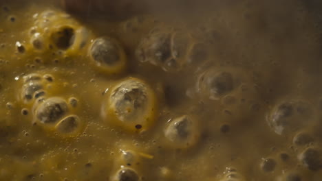 green boiling sauce texture close-up macro. cooking green curry with wooden spoon at home.