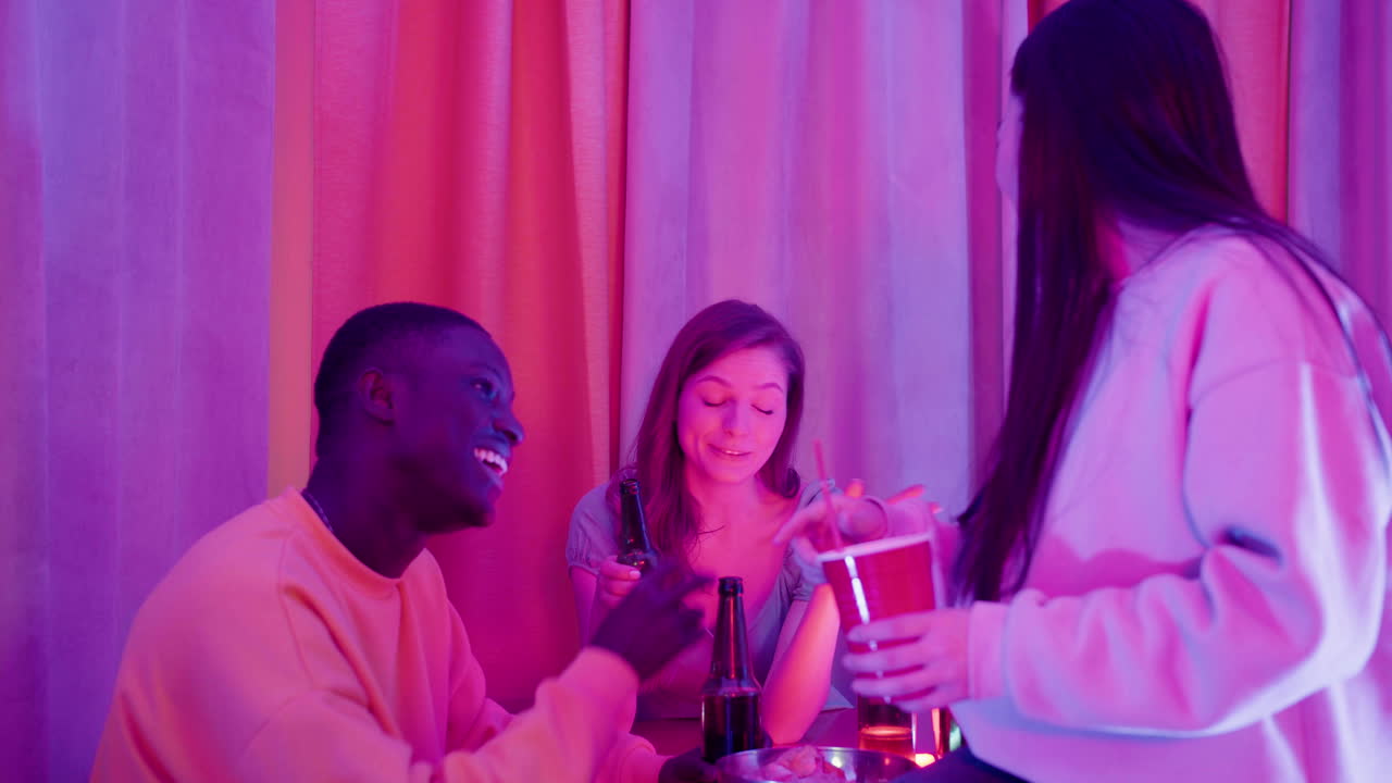 Three multiethnic young friends spending time together, talking and laughing during a party at home