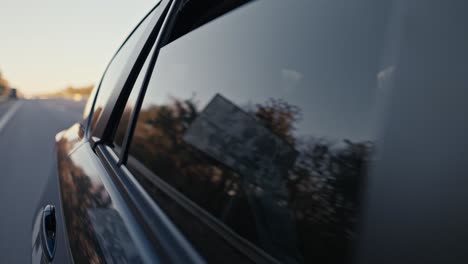 Close-up-shot-of-a-confident-man-with-Black-skin-color-and-a-beard-in-a-brown-suit-closes-the-rear-window-of-a-car-during-his-trip-in-a-modern-car