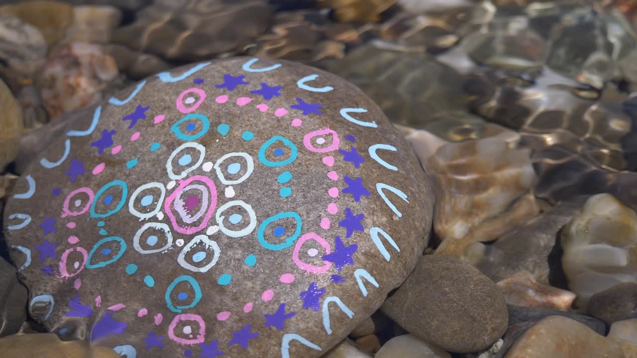 primer plano de piedra vieja coloreada en agua clara, pintada por niños en la naturaleza - niños pintando y distribuyéndola en el camino del bosque y la pradera