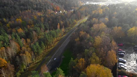 Vista-Aérea-De-Los-Coches-Que-Pasan-Por-Un-Camino-Forestal-En-Otoño-Con-Hermosos-árboles-De-Colores-Otoñales,-Concepto-De-Viaje