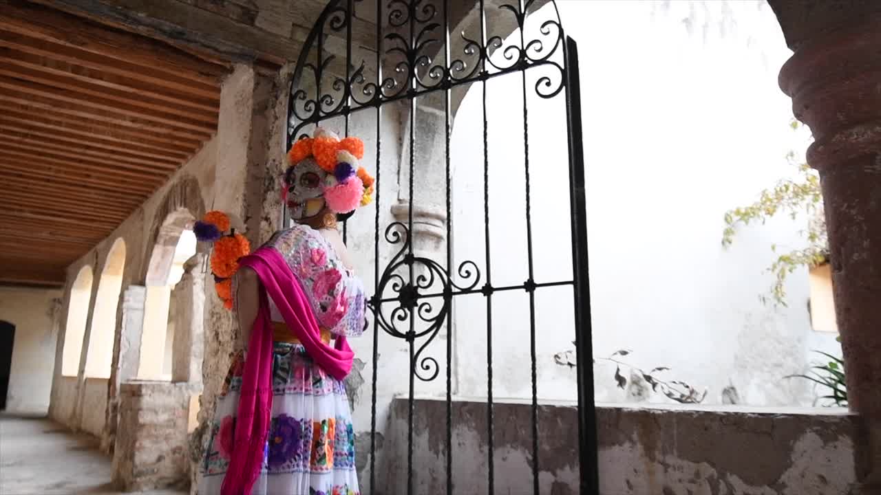 mujer catrina para el día de los muertos caminando en casa antigua con flores en la cabeza