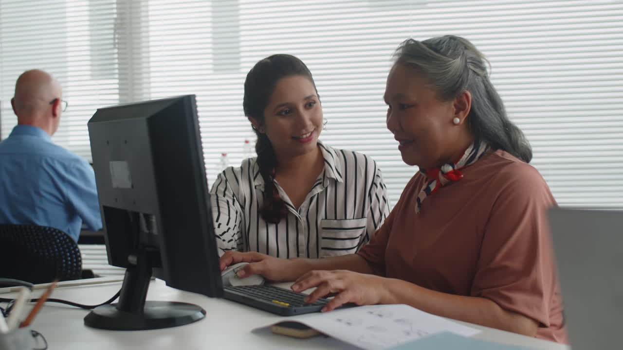 Instructor Guiding Senior Woman with Computer Skills