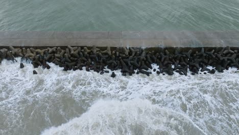 vista aérea del puerto de liepaja, muelle de hormigón, tormenta de otoño, grandes olas salpicando, día nublado, tiro de avión no tripulado a vista de pájaro