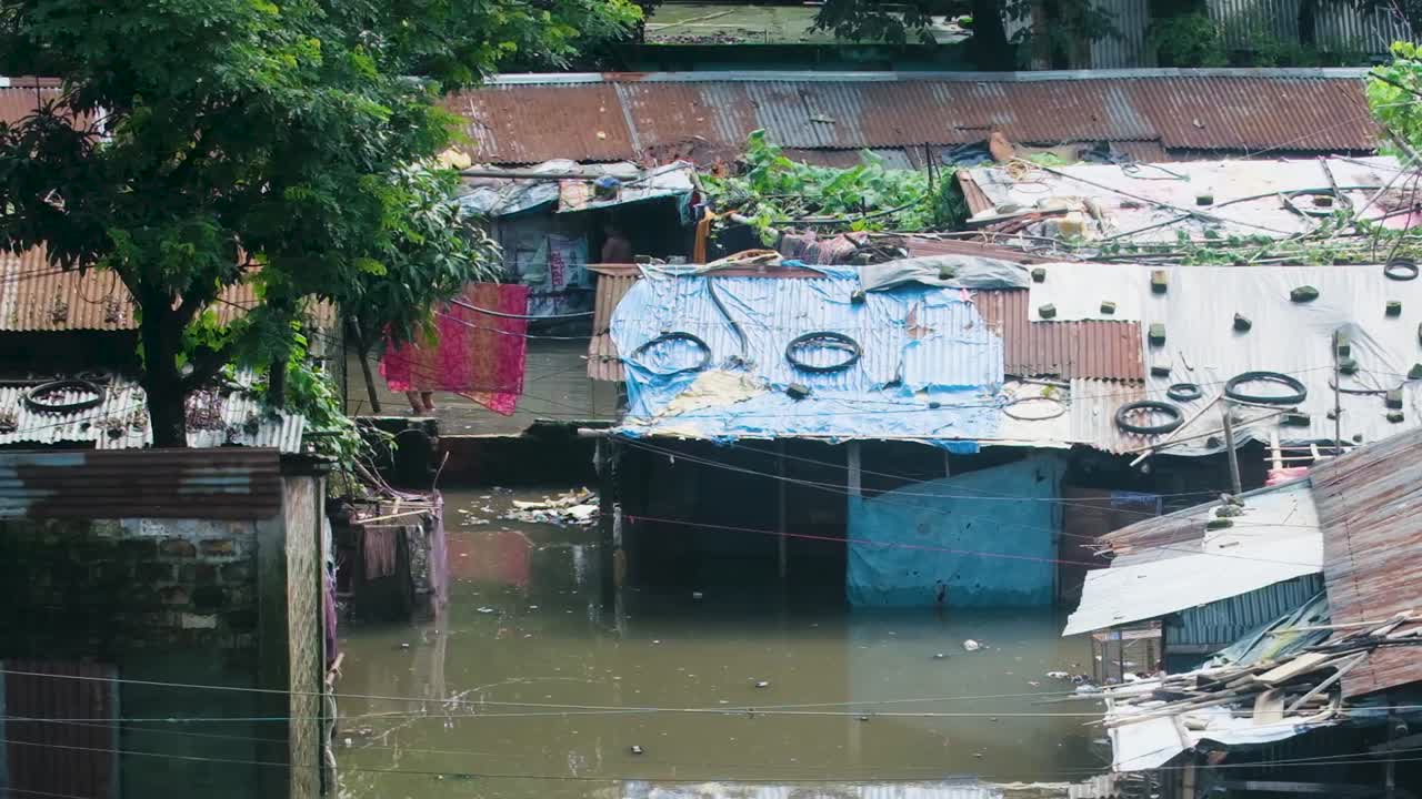 People are Affected as Floodwaters Submerge the Tin Shed Homes in the Impoverished Area Along the River in Bangladesh, South Asia - Handheld Shot