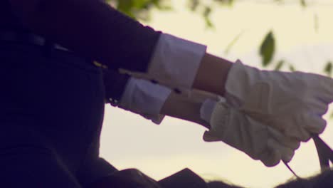 cinematic close up shot of a woman riding a horse in slow motion with a black and white outfit and matching white gloves focusing on her face and body, slomo