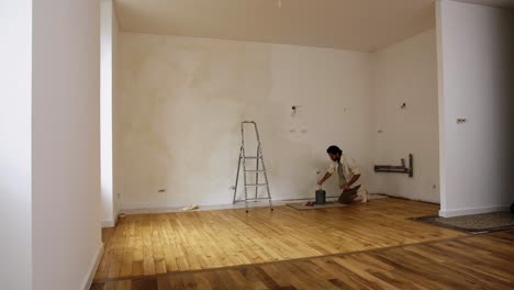 a man painting with limewash paint inside an empty room