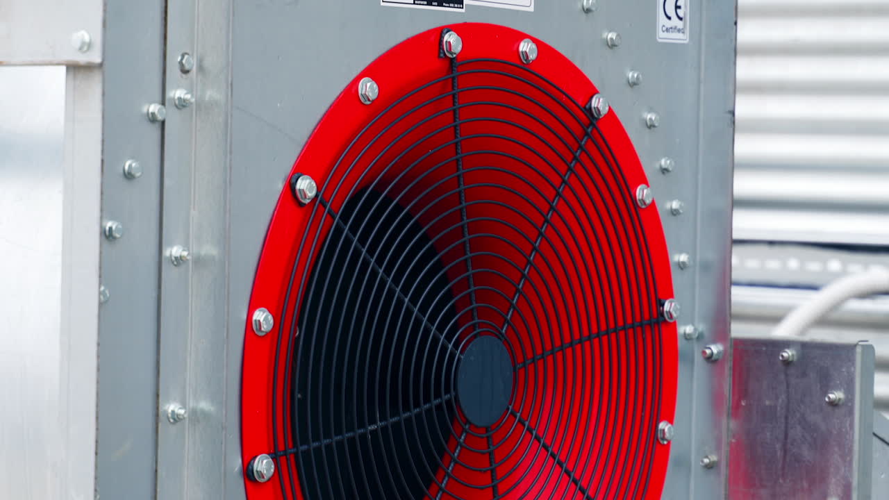 Big red ventilator at the granary tank. Fan for drying grain at the large agricultural plant during crops processing. Close up.