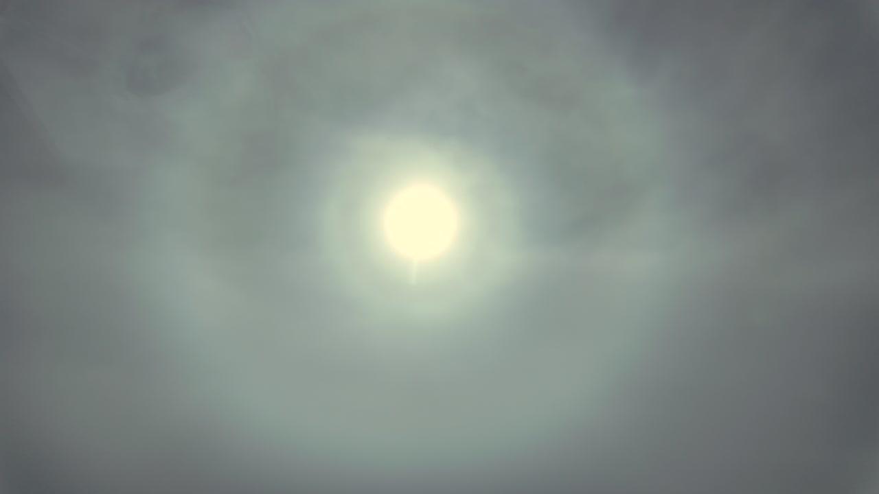 Vista aérea do halo de um sol pálido velado por nuvens etéreas na alta atmosfera. Imagens feitas da cabine de um jato.