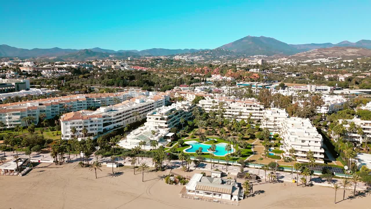 Vista aerea dei resort sul lungomare di Puerto Banús con piscine di hotel, lungomare costeggiato da palme e paesaggio turistico di lusso lungo la costa di Marbella, Costa del Sol, Spagna. Puerto Banús