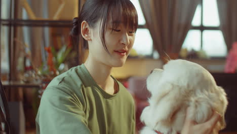 기쁜 아시아 여성이 집에서 개를 만지고 있습니다.