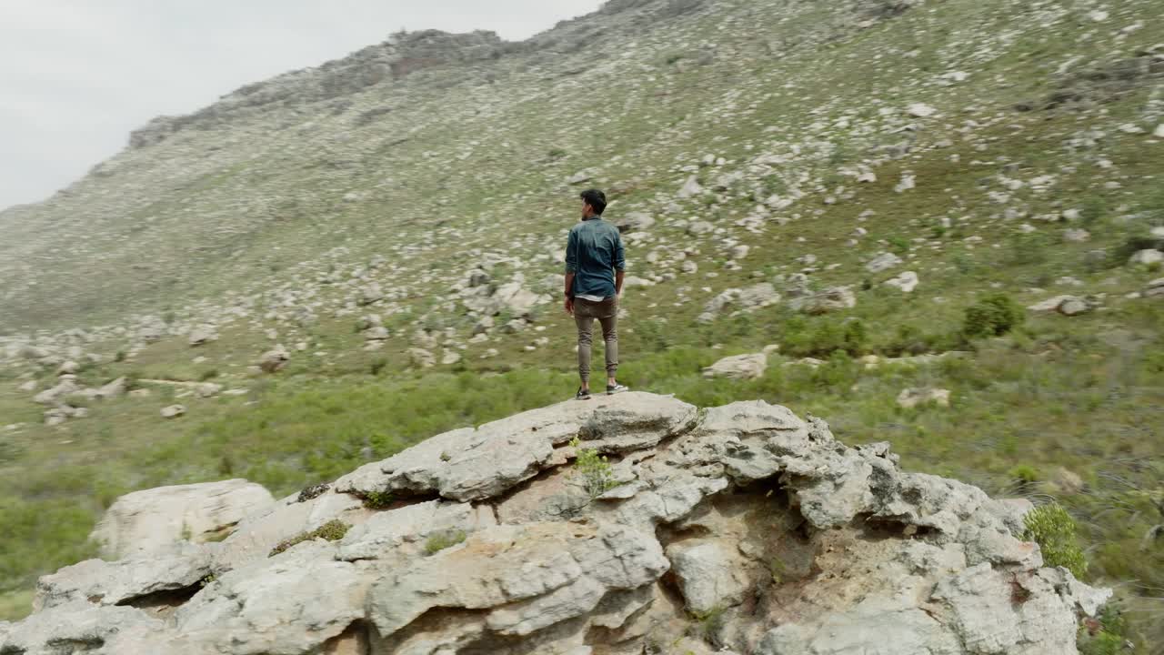 Young man stands on a rock in the Cederberg Wilderness Area in South Africa - drone rotates around the rock