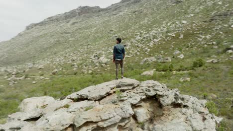 young man stands on a rock in the cederberg wilderness area in south africa - drone rotates around the rock