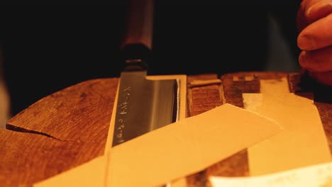 person meticulously sharpens knife on a wooden block.