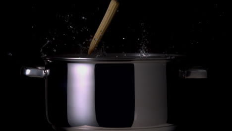 vegetables falling into pot on black background