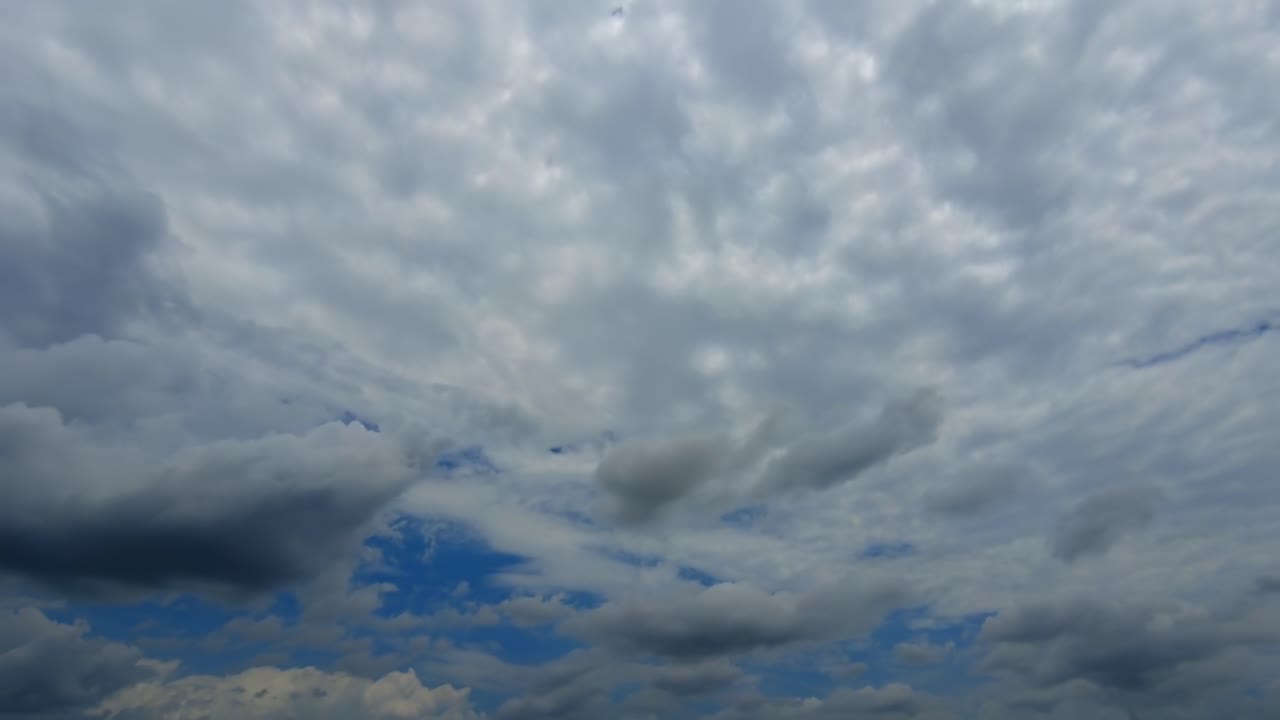 Timelapse of beautiful fluffy clouds moving from left to right with the sun hidden above the clouds in isolate blue sky