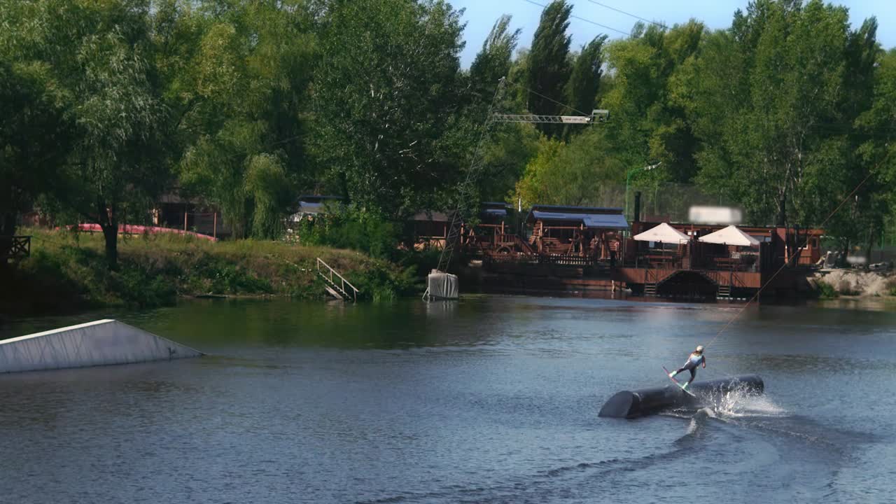 Ragazza sportiva che pratica wakeboard in un wake park con cavo. Concetto di stile di vita sano.