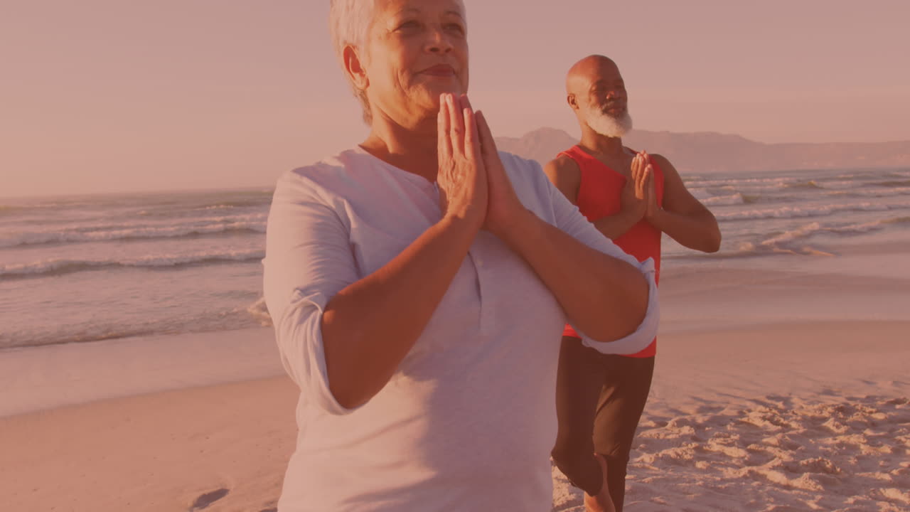 Coppia anziana afroamericana che pratica yoga insieme in spiaggia