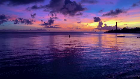 Vivid-Colourful-Sunset-with-Silhouette-of-fisherman-ocean-with-ripples