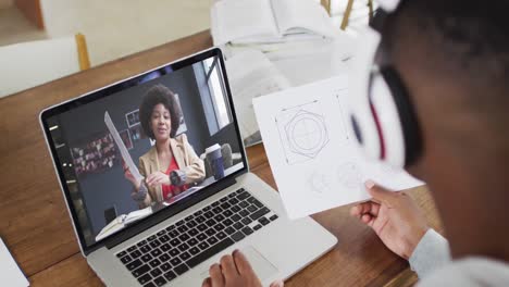 Estudiante-Universitario-Afroamericano-Sosteniendo-Notas-Mientras-Realiza-Una-Videollamada-En-Una-Computadora-Portátil-En-Casa