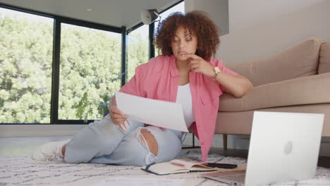 reviewing documents, woman sitting on floor with laptop and notebook nearby