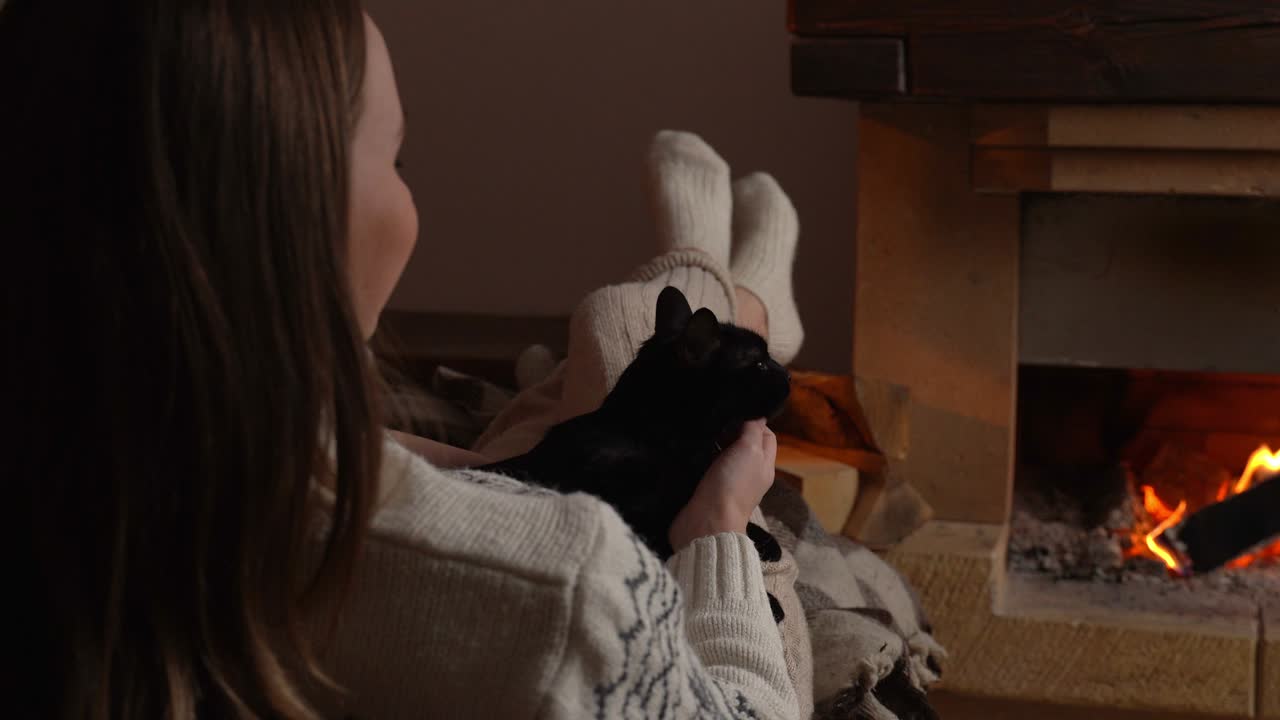 여자 손 애완동물 귀여운 검은 고양이가 벽난로 앞에서 그녀의 무에서 잠을 자고