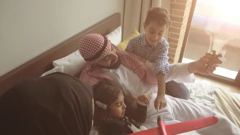 middle eastern family at home on couch. father playing with his kids.