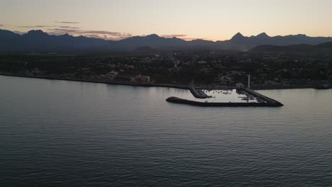 Sunset-drone-landscape-at-marine-bay-of-Loreto-baja-california-Mexican-aerial-sunset-skyline-along-Mountain-range,-golden-hour-horizon-colors