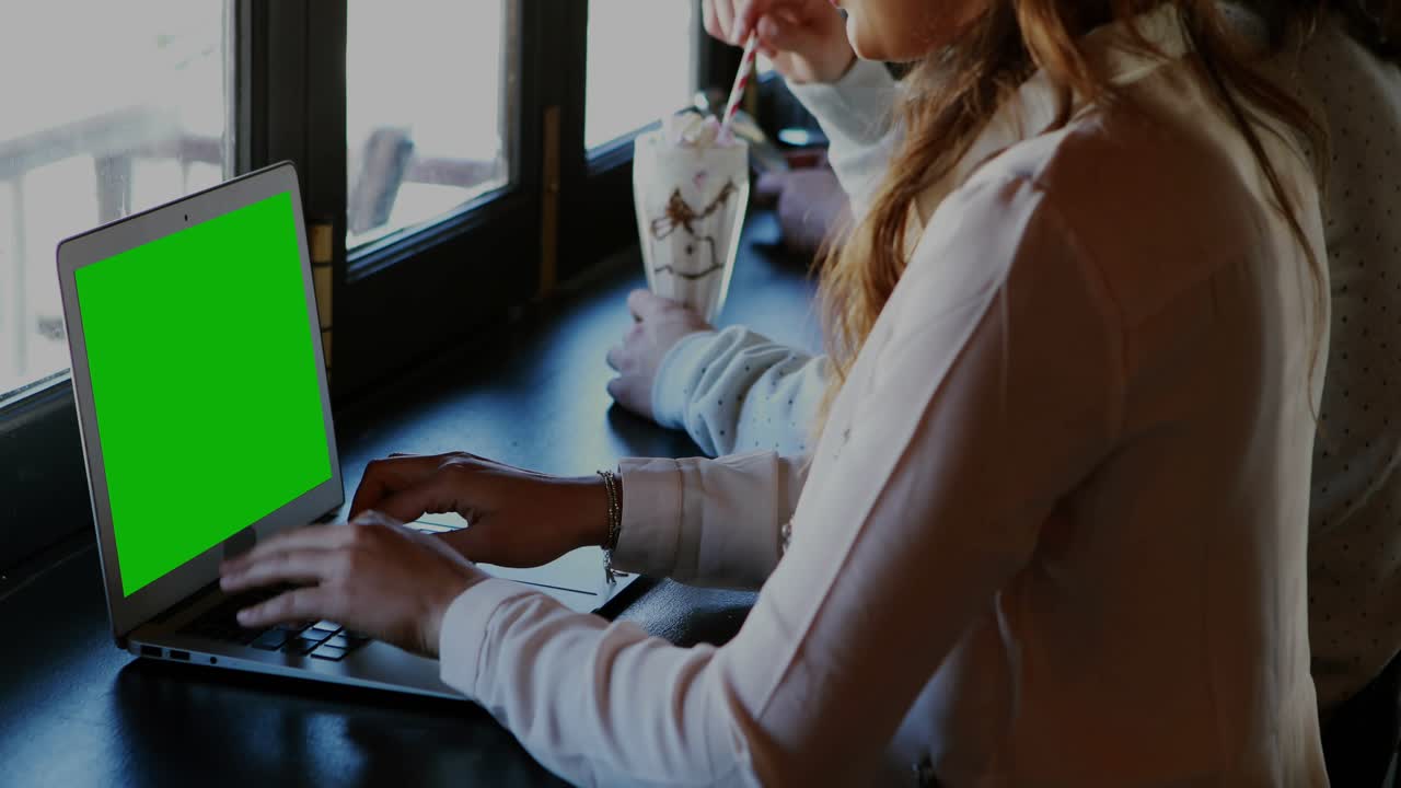 Kvinde, der skriver på bærbar computer ved en cafédisk, hvilket får AR-dashboards til at overlappe skrivebordet for dataanalyse