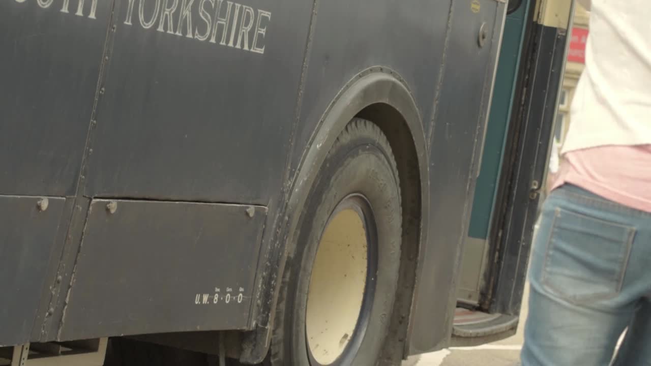 A vintage bus on a street with people nearby