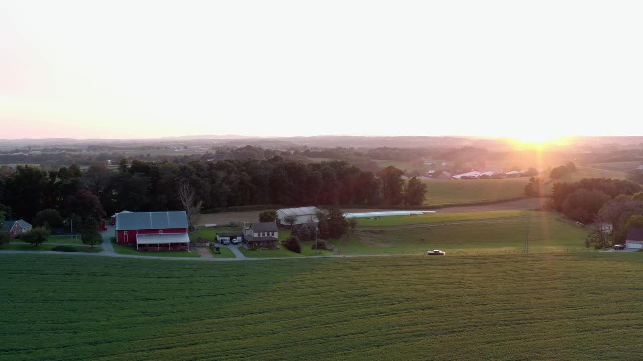 Luftfoto af lastbil, der kører gennem landskab ved sommer solopgang, solnedgang blandt grønne marker