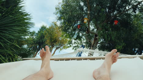 a man is resting in a hammock a first-person view in the frame only the legs are visible 4k video