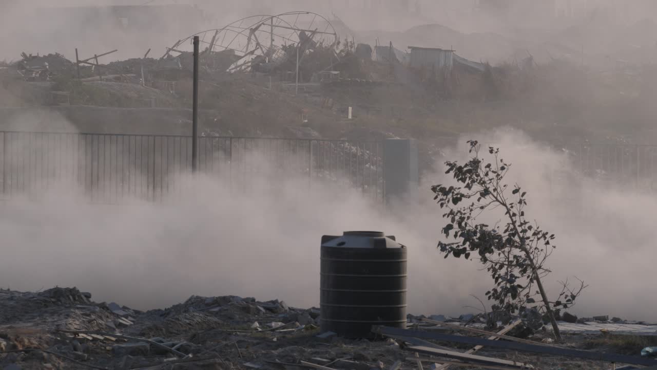 los jeeps militares de las fdi pasan por una carretera polvorienta contra el telón de fondo de los edificios destruidos por los ataques con misiles israelíes en la franja de gaza.