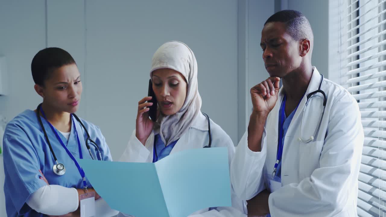 Front view of Middle-East female doctor talking on mobile phone with her colleagues in hospital