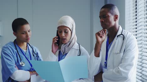 front view of middle-east female doctor talking on mobile phone with her colleagues in hospital