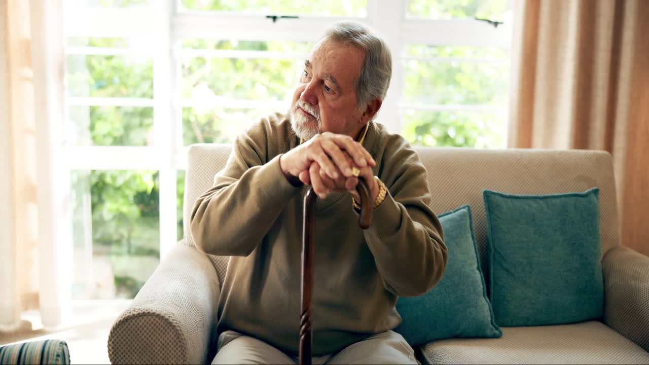 Elderly man sitting on couch with cane