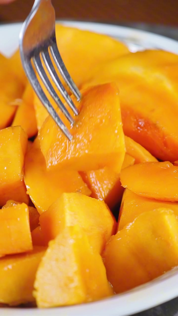 Forchetta che raccoglie un pezzo di mango fresco affettato