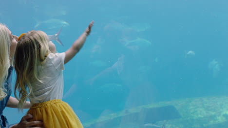 Niña-Feliz-Con-Su-Madre-En-El-Acuario-Mirando-Hermosos-Peces-Nadando-En-El-Tanque-Niño-Observando-Animales-Marinos-Con-Curiosidad-Divirtiéndose-Aprendiendo-Sobre-La-Vida-Marina-Con-Su-Madre-En-El-Oceanario