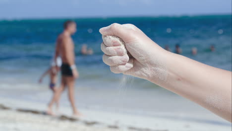 Arena-Saliendo-De-La-Mano-Femenina