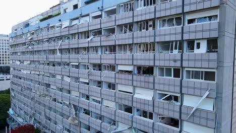 drone lowers along a building in tel aviv with broken windows and visible interior damage.