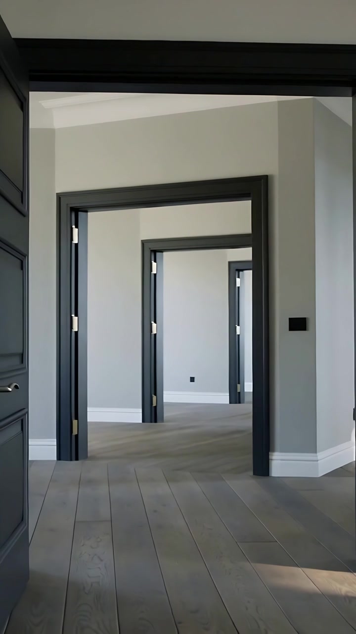 Video verticale: Telecamera che avanza rivelando telai di porte scuri allineati in una casa vuota, mostrando la luce.