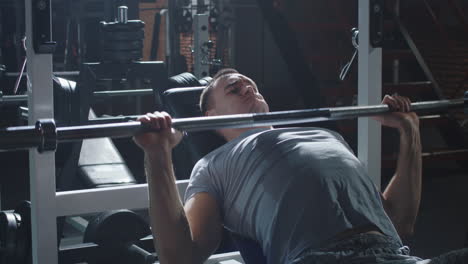 man performing bench press exercise in gym