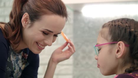 Mother-and-daughter-eating-graipe-fruit-slice-at-kitchen.-Mom-and-kid-eat-fruit