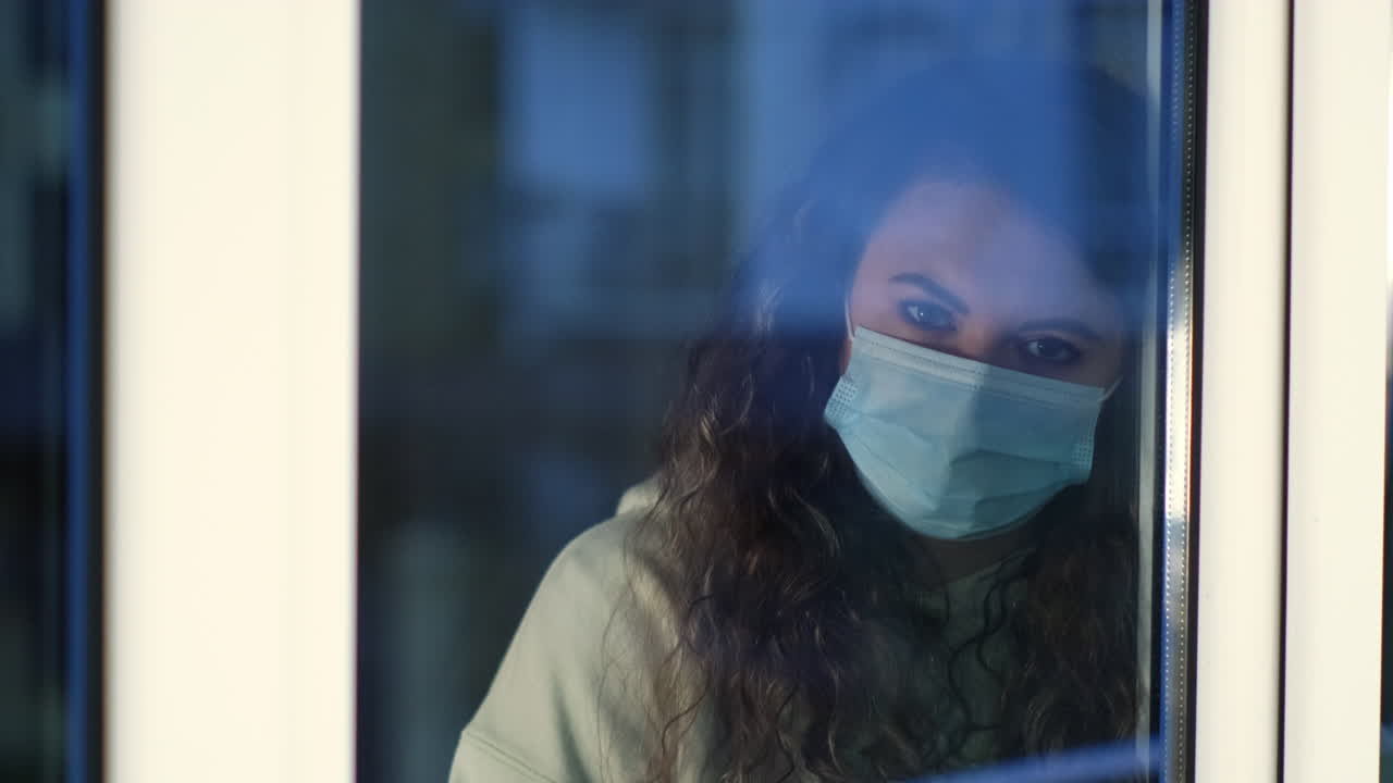 마스크를 쓰고 창밖을 바라보는 여자