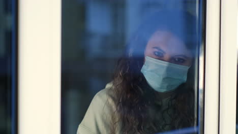 mujer mirando por la ventana, con una máscara