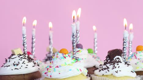 cup cakes with cream and crumbs and burning candles for birthday party. close up